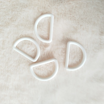 Argolas em forma de D de plástico branco sobre superfície felpuda bege claro