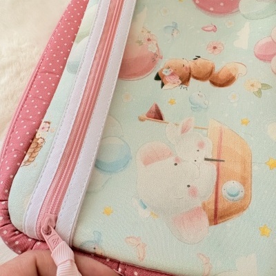 Necessaire infantil colorida com fecho rosa e padrão de animais e balões