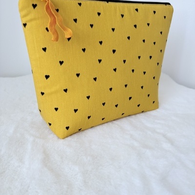 Bolsa de tecido amarelo com corações pretos e fecho zipper