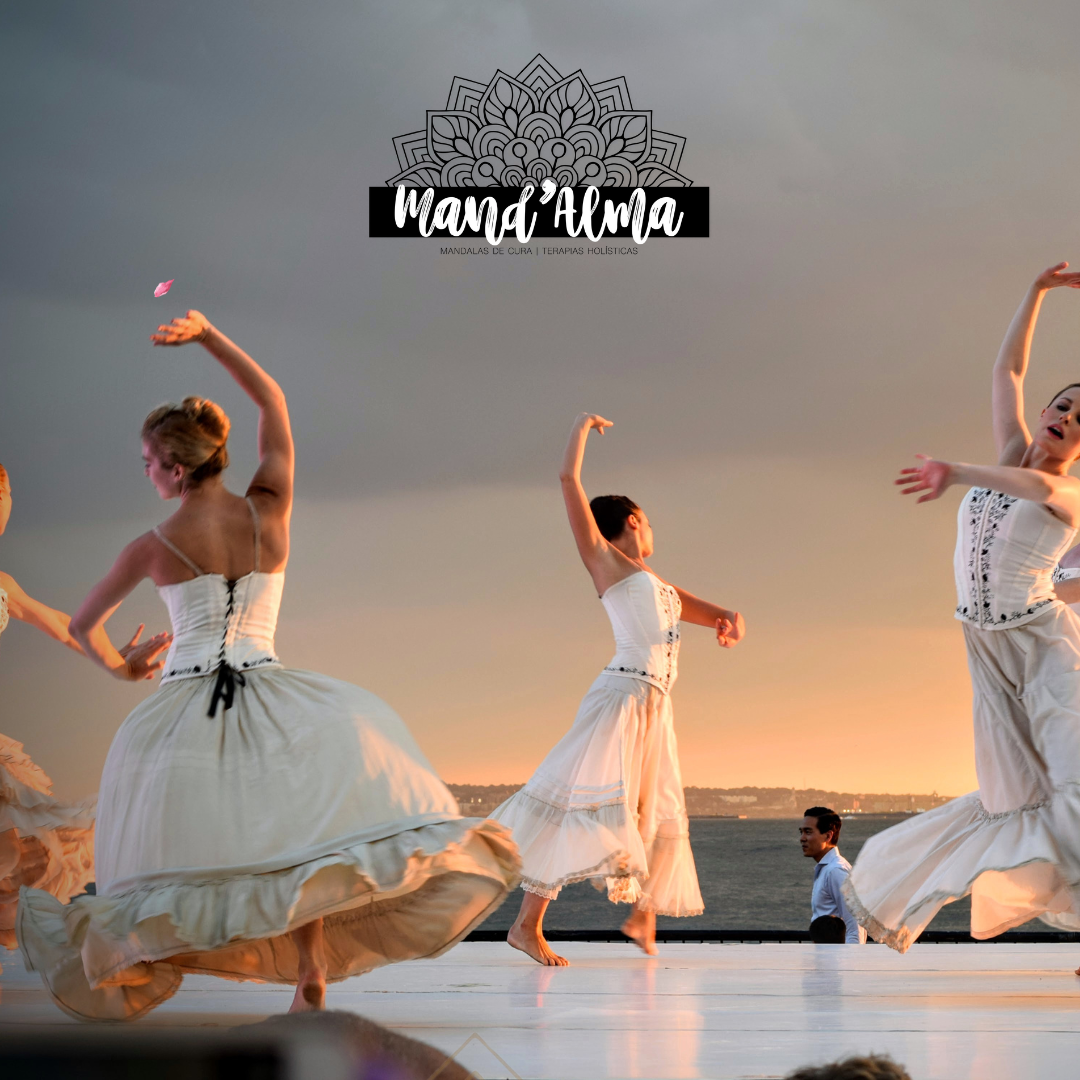 Bailarinas a dançar ao ar livre ao pôr do sol com vestidos folk brancos