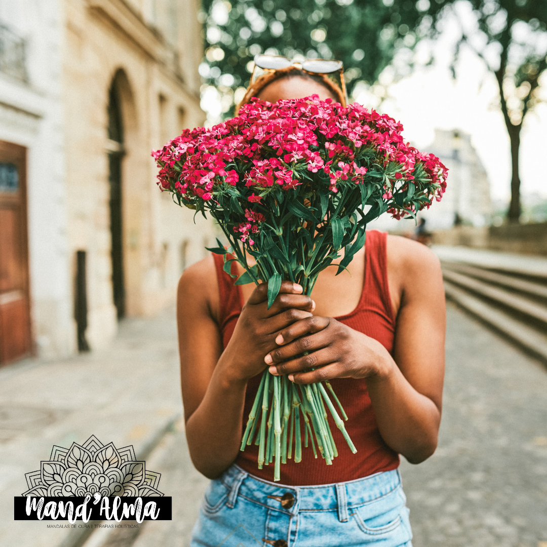 Pessoa segura ramo grande de flores cor-de-rosa num cenário urbano