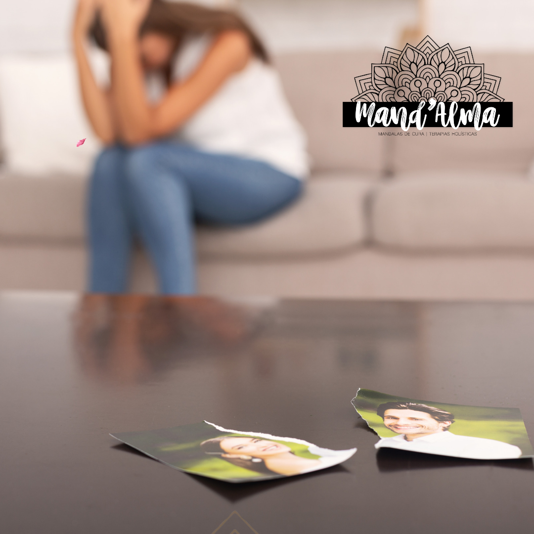 Fotografias rasgadas na mesa com mulher sentada triste ao fundo e logotipo Mand'Alma