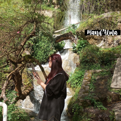 A descoberta da Paz Interior: Aceitação das Coisas Incontroláveis Mulher de vestido preto com telemóvel diante de cascata natural com vegetação