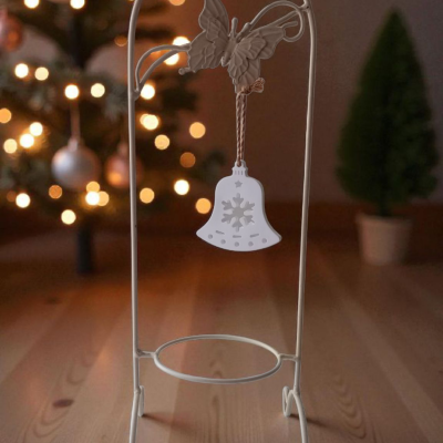 Suporte metálico branco com sino decorativo de Natal no chão de madeira