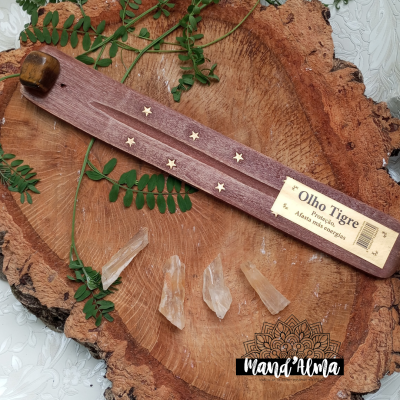 Suporte de incenso em madeira com estrelas douradas e cristal sobre madeira natural.