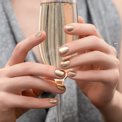 Nem tudo o que parece é... já diz o ditado "nem tudo o que luze é ouro" Mãos femininas com unhas douradas segurando taça de espumante rosé