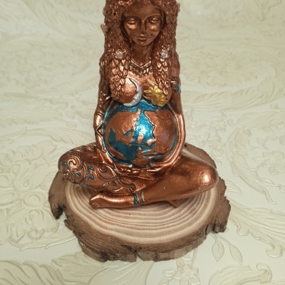 Estatueta de mulher grávida em bronze com detalhes coloridos sobre base de madeira