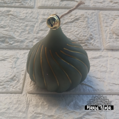 Ornamento verde-escuro com linhas douradas pendurado em azulejos brancos