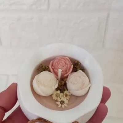 Vela decorativa branca com laço de corda e flores artificiais no topo