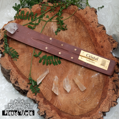 Suporte para incenso rosa com cristais e folhas verdes sobre madeira e superfície branca