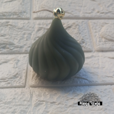 Vela verde escura em formato espiral com topo dourado sobre suporte transparente