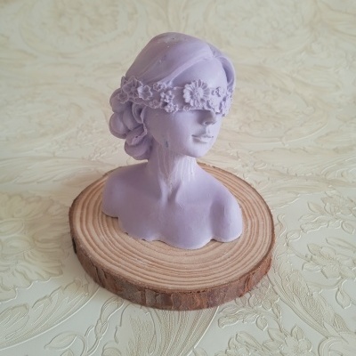 Busto decorativo lilás com faixa floral sobre base de madeira