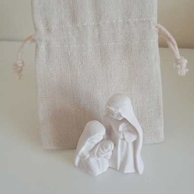 Figura pequena branca da Sagrada Família com saco de tecido cru ao fundo