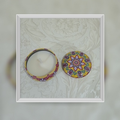 Vela aromática com tampa floral colorida sobre fundo bege texturizado