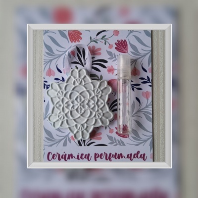 Cerâmica perfumada em forma de flor branca com frasco pequeno transparente sobre cartão floral