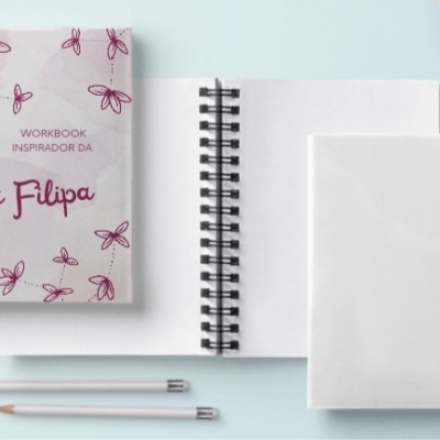 Três cadernos em espiral e dois lápis sobre mesa azul clara