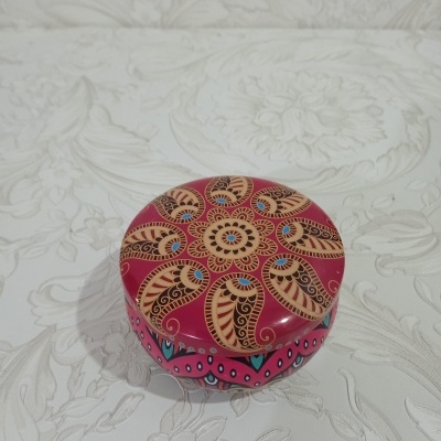 Caixa redonda decorada com padrão floral colorido sobre fundo vermelho