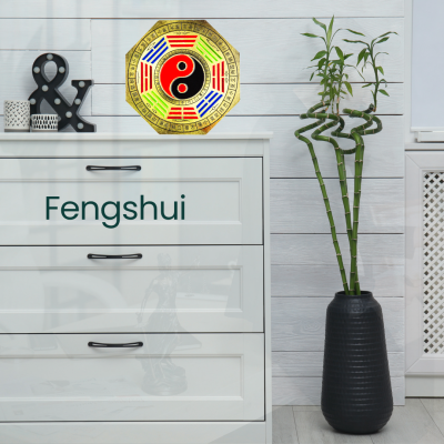 Transforma a tua casa, Transforma a tua Vida: Descobre os Benefícios do Feng Shui Adesivo decorativo com símbolo Yin Yang colorido numa parede branca ao lado de móvel branco e vaso preto com bambu da sorte