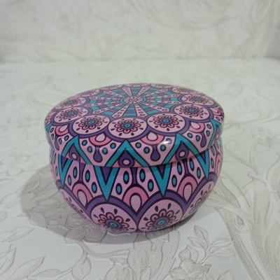Caixa redonda em metal decorada com padrão colorido floral e geométrico