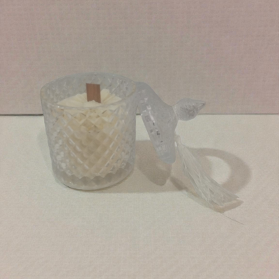 Vela branca em jarra de vidro facetado com tampa transparente pendurada