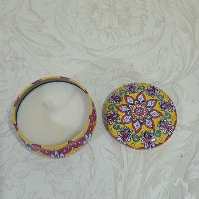 Vela branca em recipiente metálico decorado com tampa floral colorida