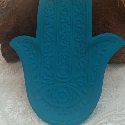 Estatueta azul em forma de mão de fatima com olho central e padrões gravados