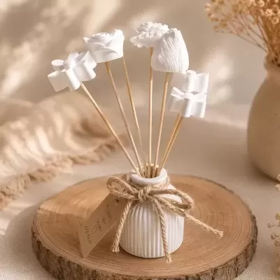 Difusor de aromas branco com flores decorativas em madeira numa placa de madeira