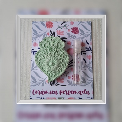 Cerâmica perfumada verde com design ornamental sobre cartão floral com frasco transparente