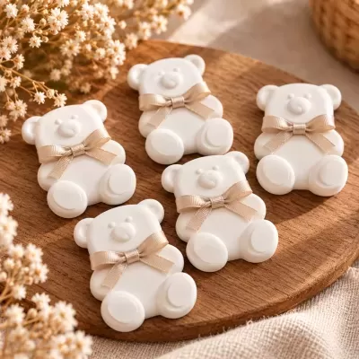 Sabonetes em forma de ursinhos brancos com laços bege num prato de madeira com flores secas