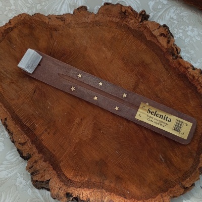 Suporte de incenso de madeira castanha com estrelas douradas sobre base de madeira amarela