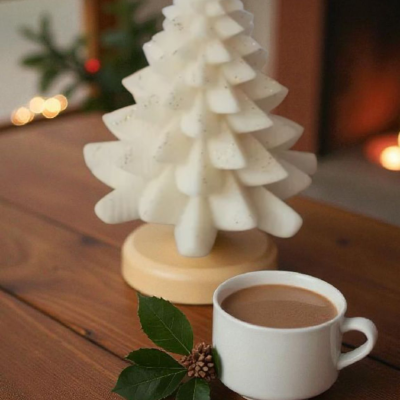 Vela em formato de árvore de Natal e chávena de café numa mesa de madeira