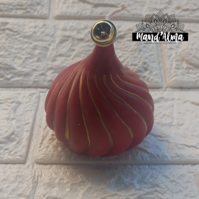 vela decorativa vermelha com detalhes dourados em suporte de vidro sobre azulejos brancos