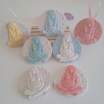 Ornamentos redondos com figuras femininas em relevo em várias cores pastel com fitas para pendurar.