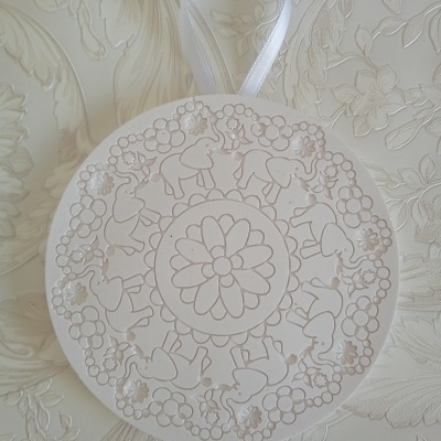 Ornamento redondo branco com desenhos florais e de cavalos/unicórnios com laço branco