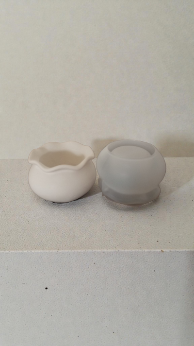 Duas pequenas tacinhas, cerâmica branca e vidro fosco cinzento, sobre superfície branca