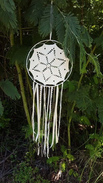 Apanhador de sonhos branco de crochê com fitas penduradas, pendurado numa árvore