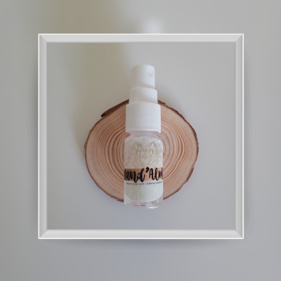 Pequeno frasco de spray transparente com tampa branca sobre disco de madeira