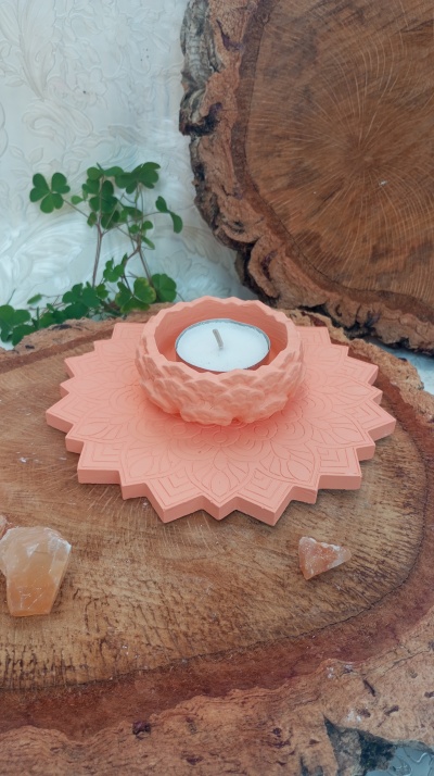 Castiçal terracota com vela, sobre disco de madeira e duas pedras pequenas ao lado