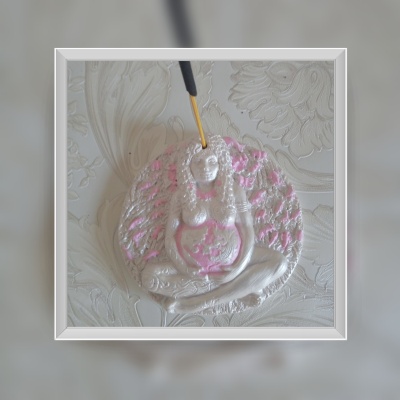 Figura decorativa feminina branca e rosa com várias mãos pendurada na parede