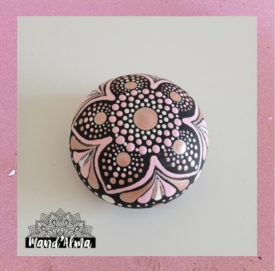 Pedra pintada com padrão floral em rosa e preto sobre fundo branco