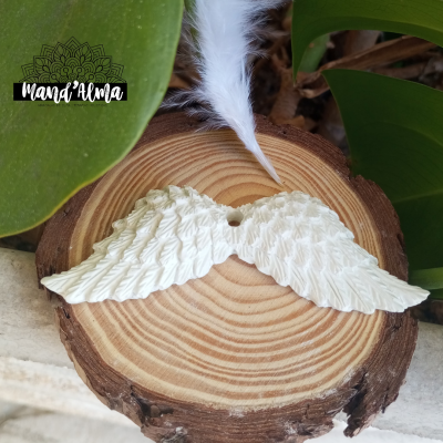 asas de anjo brancas em cerâmica sobre madeira com pena branca e folhas verdes