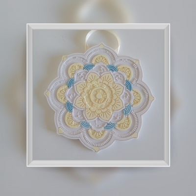 Mandala decorativa em tons creme, amarelo, branco e azul com fita para pendurar