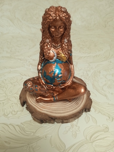 Estatueta de mulher grávida em bronze com detalhes coloridos sobre base de madeira