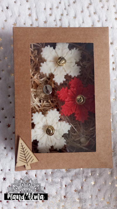 Caixa com três sinos em forma de floco de neve, dois brancos e um vermelho, com sinos dourados, em embalagem de cartão com tampa transparente