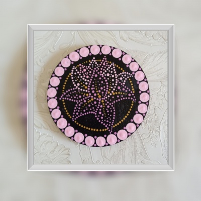 Disco decorativo redondo com padrão floral de pontos em rosa, lilás e dourado sobre fundo preto.