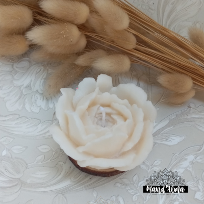 Vela em forma de flor branca sobre base de madeira com ramos secos decorativos