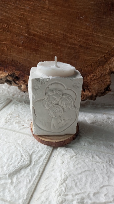 Vela branca quadrada com relevo de família sagrada sobre base de madeira
