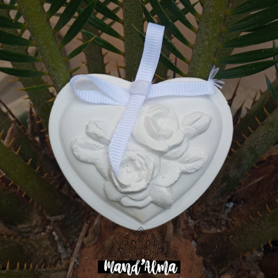 Coração branco decorativo com flores em relevo e fita branca pendurado em planta