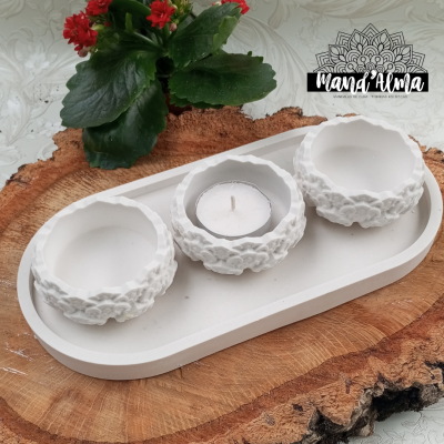 Conjunto de castiçais brancos com textura, planta com flores vermelhas e logótipo Mand' Alma