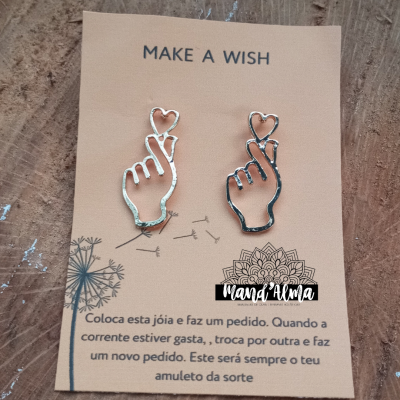 Conjunto de brincos prateados em forma de mão com dedo e coração em cartão bege com textos e desenhos.